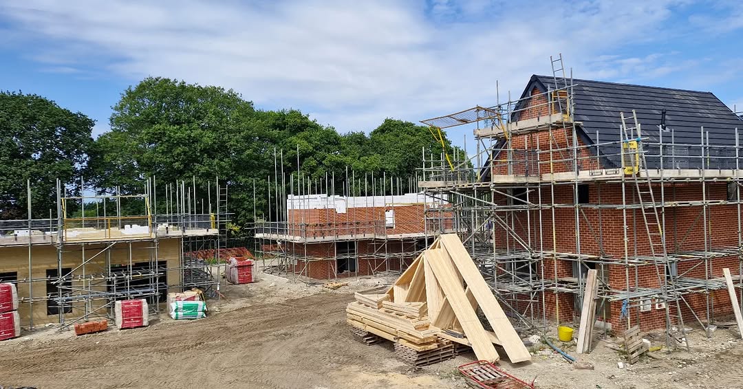 Multiple homes under construction with scaffolding and roof trusses