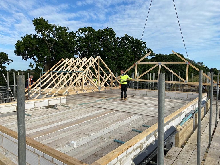 Crane lifting roof trusses into position