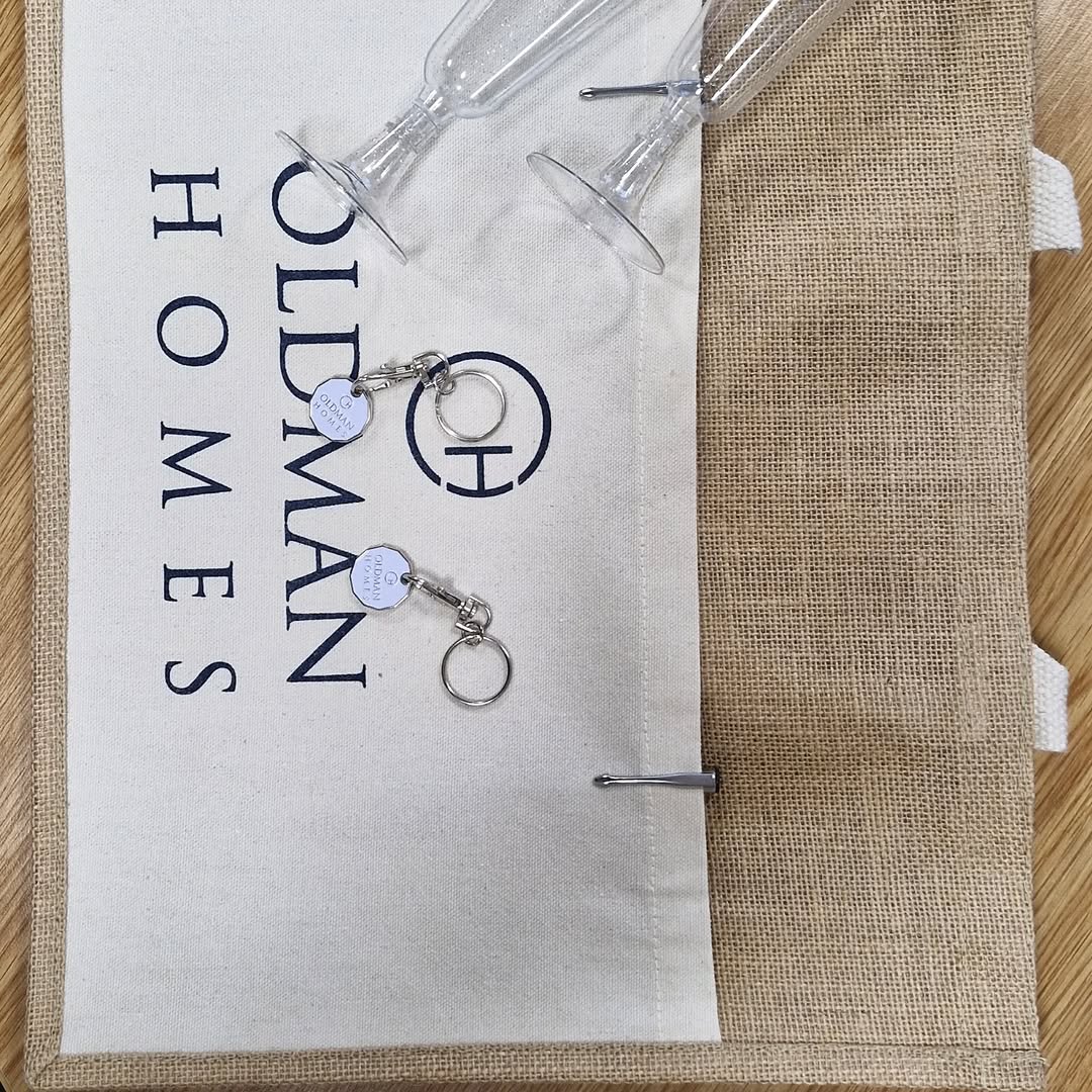 Oldman Homes branded bag with keychains and champagne flutes